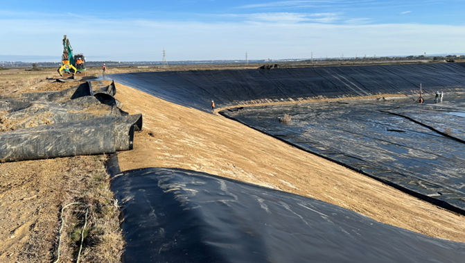Black liner material being removed from a former pond with machinary